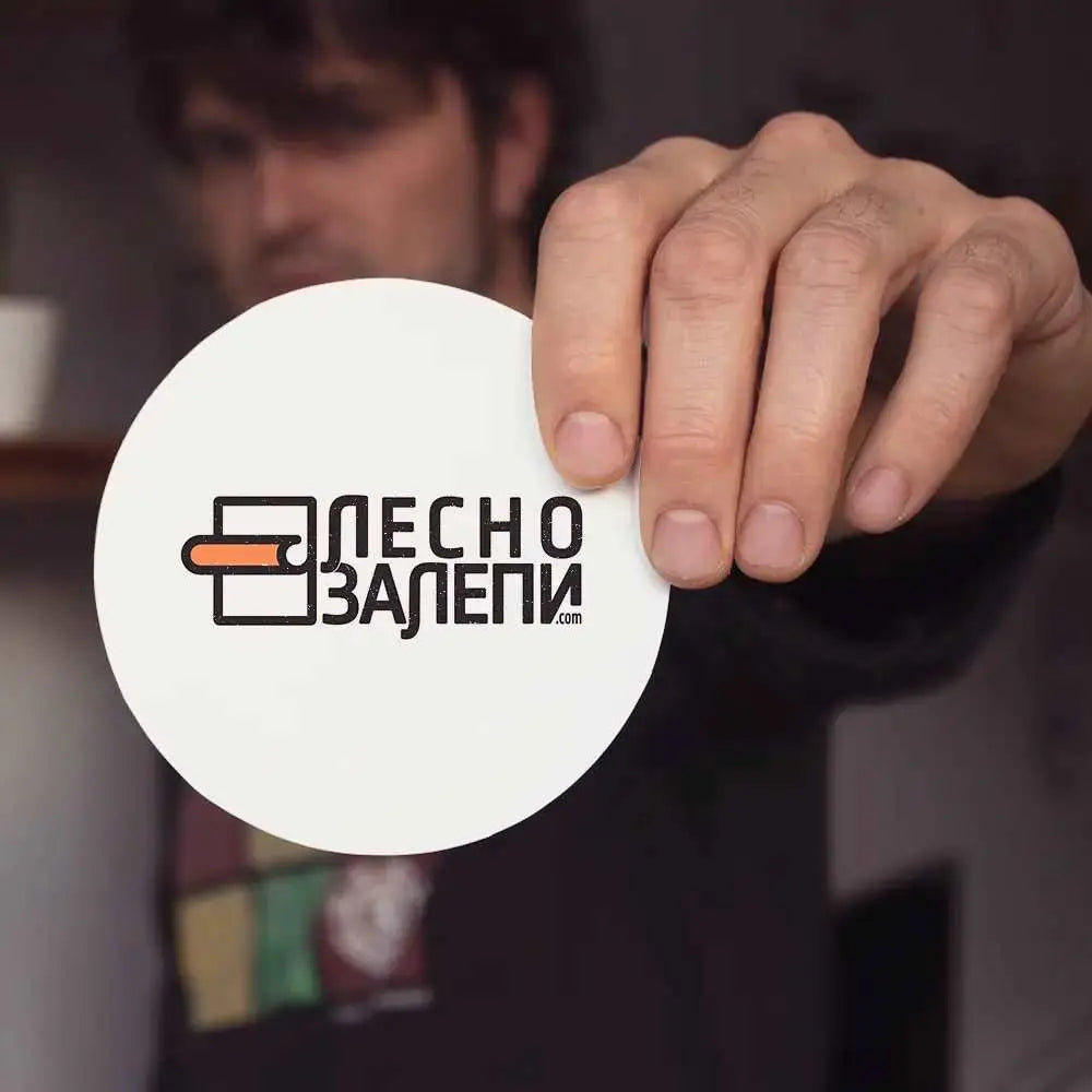 Човек държи кръгъл стикер от бяло pvc фолио с лого 'лесно залепи'