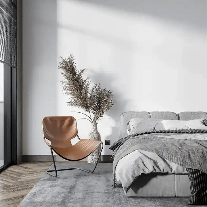 Modern bedroom featuring a stylish brown chair, cozy bed, and decorative plant in a contemporary setting.